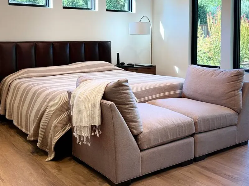 Tidy bedroom with a made bed and sofa